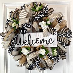 a welcome wreath is hanging on the front door with ribbon and flower decorations around it