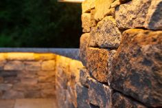 a stone wall with a light on it and some trees in the backround