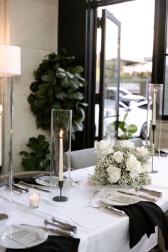 the table is set with white flowers and silverware