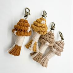 four tasseled key chains hanging from hooks on a white wall with one knot in the middle