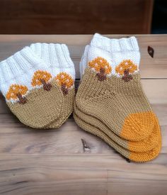 two pairs of socks with flowers on them sitting on a wooden table next to leaves