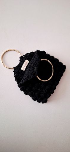 a black bag with a gold ring on it sitting on top of a white surface