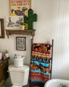 a white toilet sitting in a bathroom next to a bath tub and wooden shelf with pictures on it