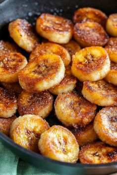 some sugared bananas are in a pan on a green table cloth and is ready to be eaten