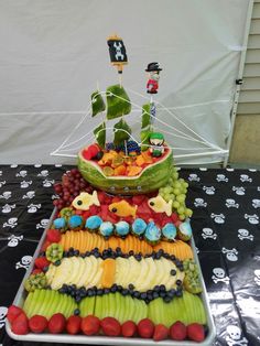 a boat made out of fruit is sitting on a table with other foods and decorations