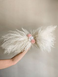 a person holding a fake flower and feather in their hand