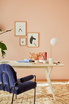 a blue chair sitting in front of a table with pictures on the wall behind it