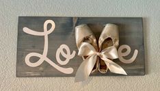 a pair of ballet shoes hanging on a sign with the word love painted on it