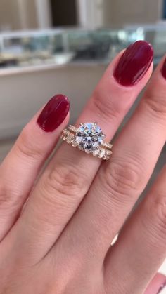 a woman's hand with two rings and a red manicure