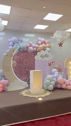 a table topped with balloons and lights next to a sign that says alylna