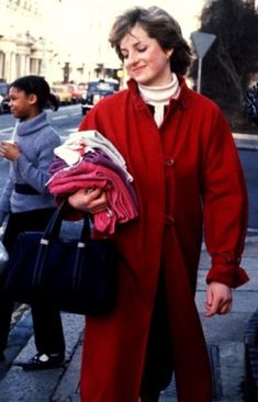 a woman is walking down the street with her hand in her pocket and holding clothes