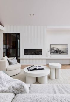 a living room with white furniture and a large painting on the wall behind the fireplace