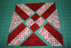 a red and white quilted block sitting on top of a green cutting mat next to a knife