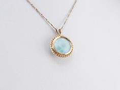 Larimar is called the sea stone, and this gorgeous pendant provides an excellent example of why! The rope-twist framework of yellow gold brings warmth and richness to the larimar, pulling the waves of seafoam green forward and swirling them with the other shades. This pendant does not come with the chain shown. Please feel free to contact us, we will help you find the perfect chain for your style and budget! Metal: 14K Yellow Gold Gem: Larimar Gem Measurements: 12.0 mm, Round Measurements: 17 x Hallmarked Larimar Jewelry, Elegant Larimar Pendant Jewelry, Larimar Gemstone Necklace For Anniversary, Anniversary Larimar Gemstone Necklace, Elegant Larimar Cabochon Jewelry, Elegant Round Larimar Jewelry, Vintage Gold Pendant, Blue Stone Pendant, Bridal Jewelry Vintage