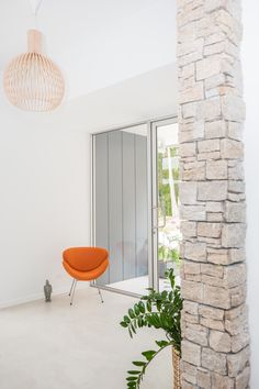 an orange chair sitting in the middle of a living room next to a tall window