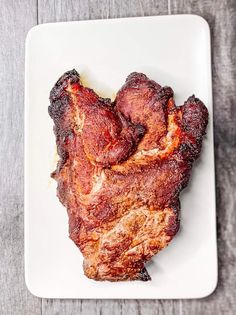 a white plate topped with meat on top of a wooden table