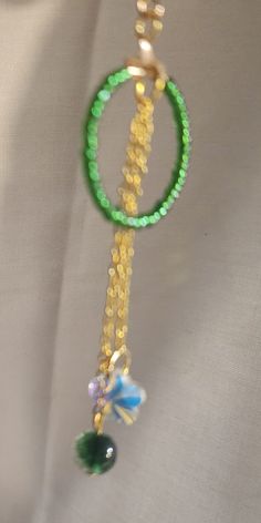 Green glass seed beads make the hoop hanging  from a gold earring hook pop.  Hanging from the center are two dainty gold colored chains holding a sparkling crystal on one and a green glass bead on the other.  Perfect to add to your outfit for the St Patrick’s Day Party Gold Beaded Necklaces For May Birthstone, Green Round Jewelry With Tiny Beads, Green Jewelry With Tiny Beads, Gold Glass Jewelry With Dangling Beads, Green Glass Beaded Chain Jewelry, Gold Beaded Necklaces With Czech Glass And Dangling Beads, Green Glass Jewelry With Beaded Chain, Green Tiny Beads Necklace For Party, Green Tiny Beaded Necklace For Party