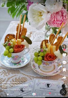 two cups filled with food sitting on top of a table next to flowers and cards