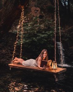 a woman laying down on a floating bed in the water while reading a book and smiling