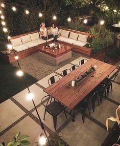 two people sitting at a table in the middle of an outdoor patio with string lights