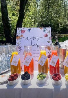 a table topped with cups filled with different types of fruit and drinks next to a sign