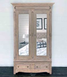 an armoire with mirrored doors and drawers in the corner, against a white wall