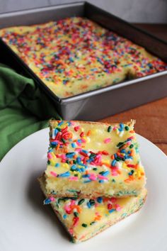 two pieces of cake with sprinkles on a plate next to a pan