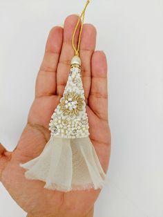 a hand holding a small white christmas tree ornament