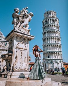 a woman is standing in front of the leaning tower