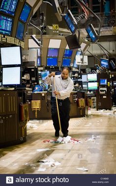 a man cleaning the floor in an office with lots of monitors and televisions on the walls