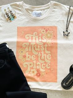 Introducing our "This Must Be The Place" graphic tee, featuring a 70s retro floral design in orange cream vintage colors. This tee is the perfect combination of retro and modern style. Made with high-quality materials, it is both comfortable and durable. Wear it with your favorite jeans or shorts for a casual yet fashionable look. Get yours today and make a statement wherever you go! Retro Orange T-shirt With Screen Print, Retro Orange T-shirt For Spring, Retro Cream Tops With Graphic Print, Retro Cream Top With Graphic Print, Beige Retro Crew Neck T-shirt, Retro Beige Crew Neck T-shirt, Vintage Cream Tops With Letter Print, Retro Orange Cotton T-shirt, Retro Beige Cotton T-shirt