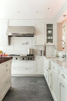 a large kitchen with white cabinets and marble counter tops, along with an island in the middle