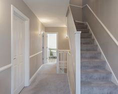 an empty hallway with stairs leading up to the door and another room in the background