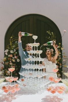 a newly married couple standing in front of a wedding cake with wine glasses on it