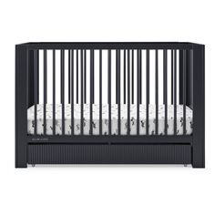 a black crib with white sheets on it