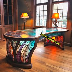 a desk with stained glass on it in front of two large windows and floor lamps