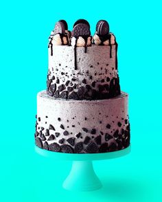 a chocolate cake with oreo cookies and cream frosting on top, sitting on a blue pedestal