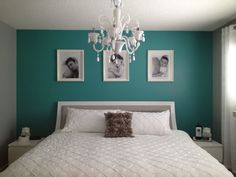 a white bed in a room with pictures on the wall and a chandelier