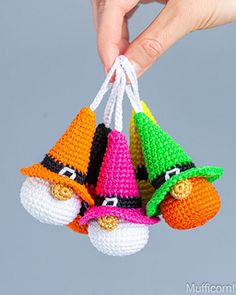 three crocheted gnomes hanging from a string with one being held by someone's hand