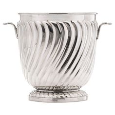 a large silver vase with wavy lines on the top and bottom, sitting on a pedestal