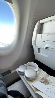 the interior of an airplane with two round windows and white objects in front of it