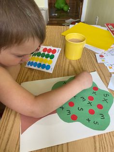 a young boy sitting at a table working on an art project with paper and glue