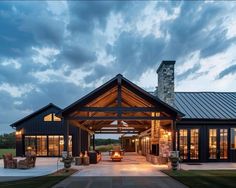 a large house with a covered patio and stone fireplaces on the front porch at dusk