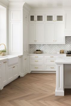 a large kitchen with white cabinets and wood flooring, along with marble counter tops