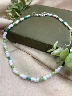 a green and white beaded necklace sitting on top of a book