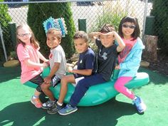 several children are sitting on an inflatable float at the park and posing for a photo