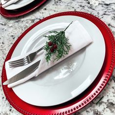 a white plate topped with a fork and knife next to a red rimmed plate