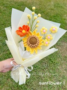 a hand holding a bouquet of flowers made from crocheted yarn and paper towels