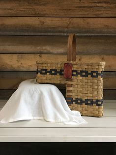 a basket and blanket sitting on top of a white shelf next to a wooden wall