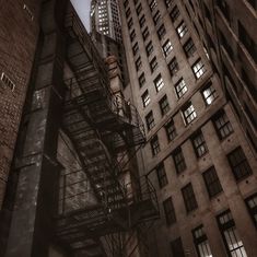 the fire escape is in between two tall buildings at night, with skyscrapers lit up behind it